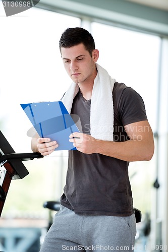 Image of trainer with clipboard standing in a bright gym