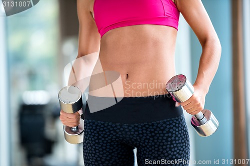 Image of lifting some weights and working on her biceps in a gym