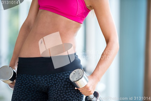 Image of lifting some weights and working on her biceps in a gym