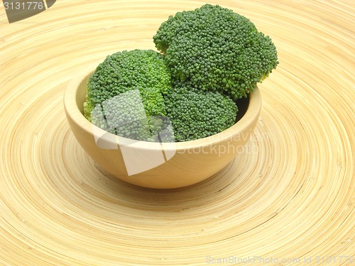 Image of Wooden bowl with broccoli on bamboo plate