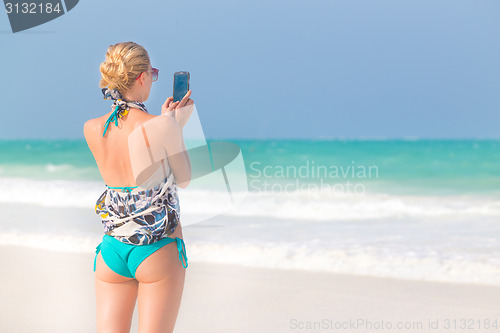 Image of Woman taking photo on the beach.