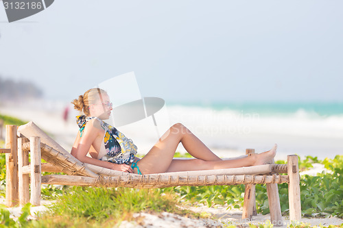 Image of Woman sunbathing on tropical beach.