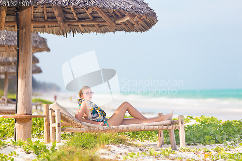 Image of Woman sunbathing on tropical beach.