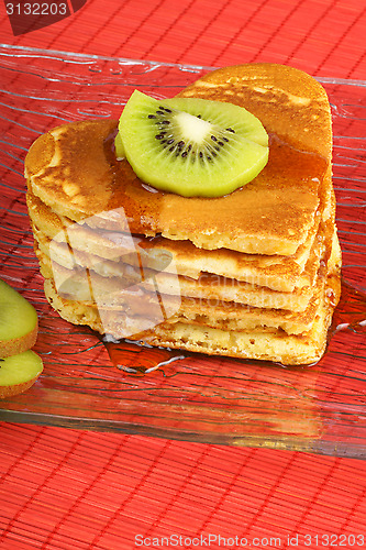 Image of Stack of heart-shaped pancakes with syrup and kiwi fruit