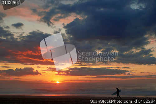 Image of Surfer on the ocean beach at sunset or sunrise