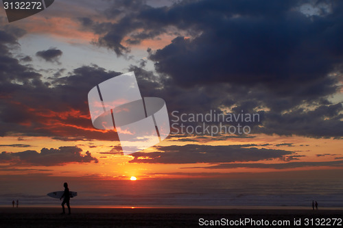 Image of Surfer on the ocean beach at sunset or sunrise