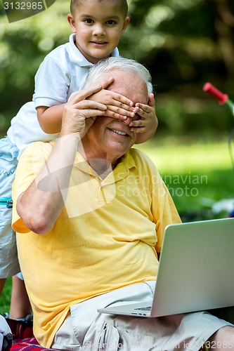 Image of grandfather and child using laptop