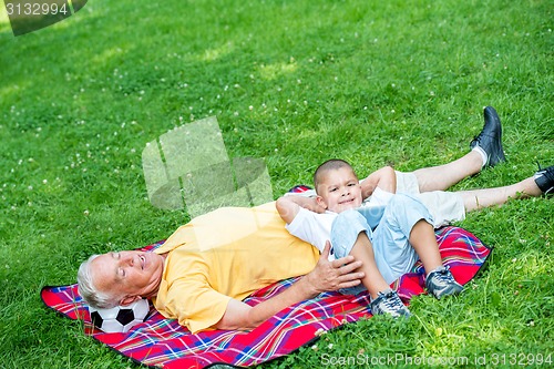 Image of grandfather and child in park using tablet