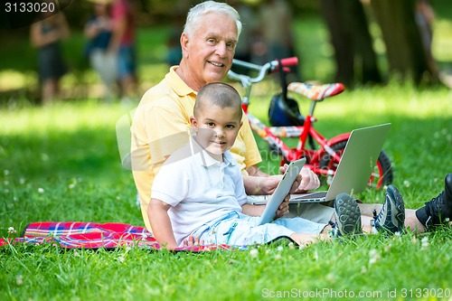 Image of grandfather and child in park using tablet