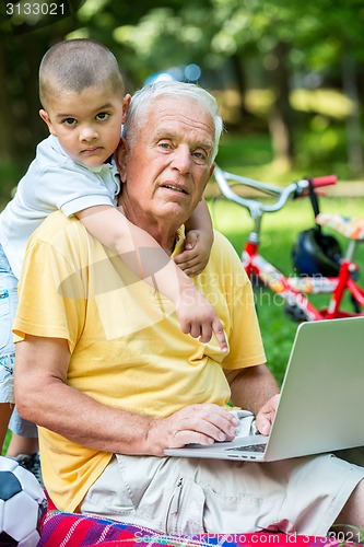 Image of grandfather and child using laptop