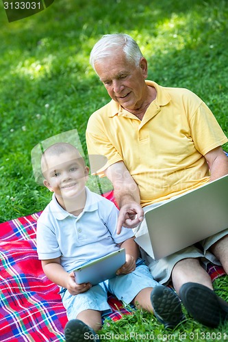 Image of grandfather and child using laptop