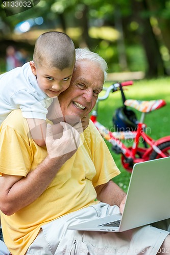 Image of grandfather and child using laptop