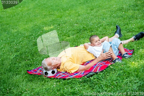 Image of grandfather and child in park using tablet