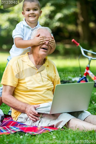 Image of grandfather and child using laptop