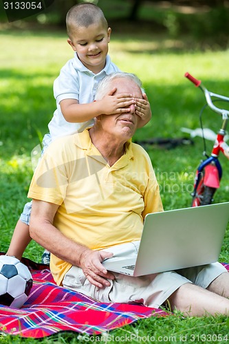 Image of grandfather and child using laptop