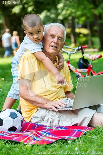 Image of grandfather and child using laptop