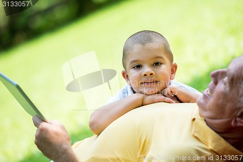 Image of grandfather and child in park using tablet