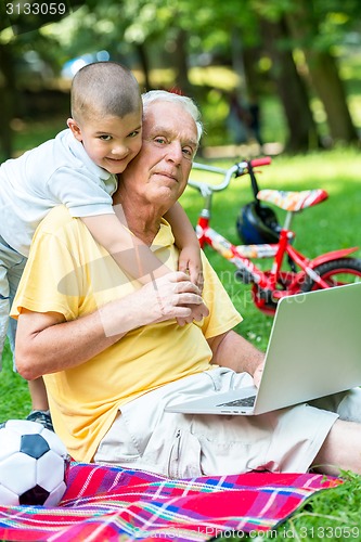 Image of grandfather and child using laptop