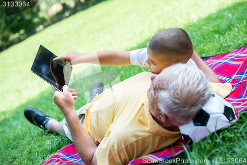 Image of grandfather and child in park using tablet