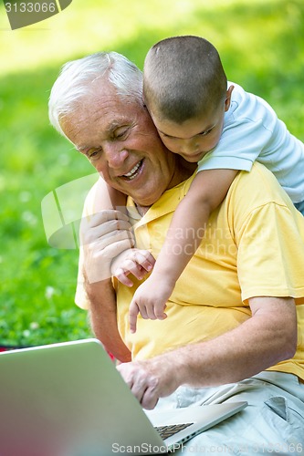 Image of grandfather and child using laptop