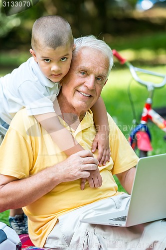 Image of grandfather and child using laptop