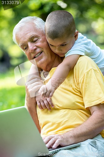 Image of grandfather and child using laptop