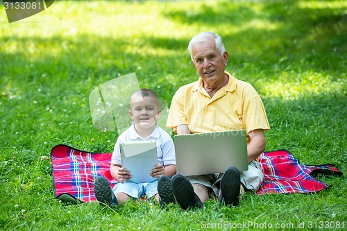 Image of grandfather and child in park using tablet
