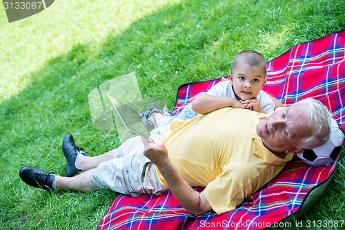 Image of grandfather and child in park using tablet