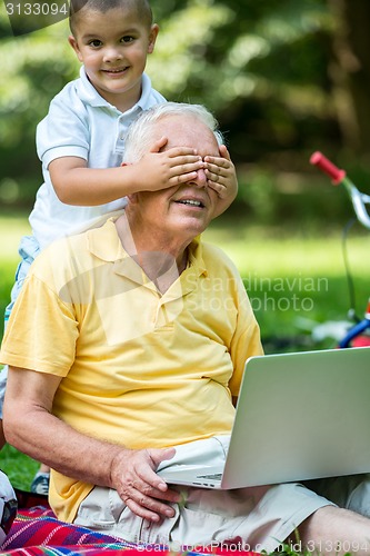 Image of grandfather and child using laptop