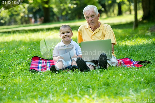 Image of grandfather and child in park using tablet