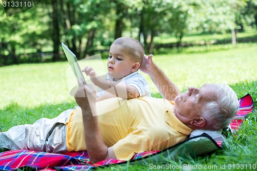 Image of grandfather and child in park using tablet
