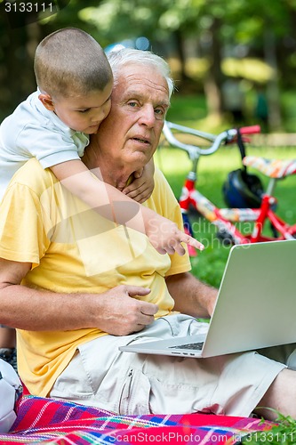 Image of grandfather and child using laptop