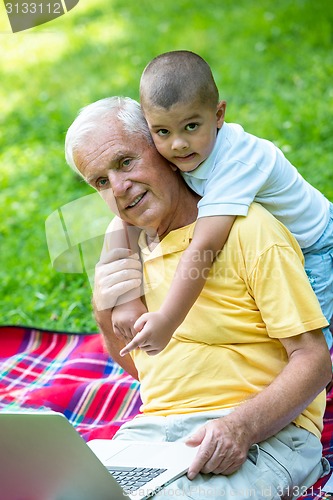 Image of grandfather and child using laptop