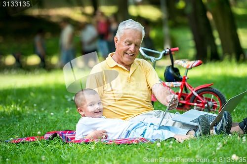 Image of grandfather and child using laptop