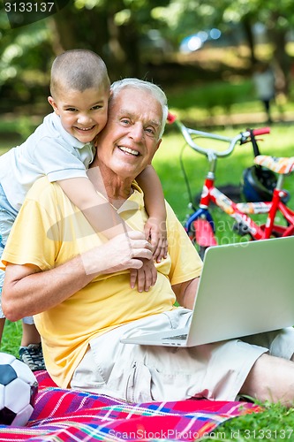 Image of grandfather and child using laptop