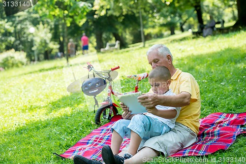 Image of grandfather and child in park using tablet