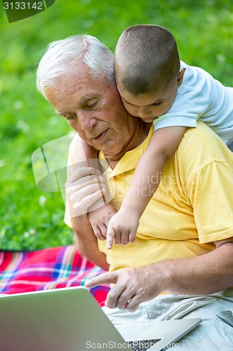 Image of grandfather and child using laptop