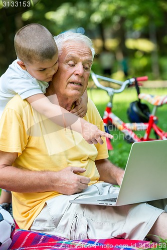 Image of grandfather and child using laptop