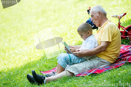 Image of grandfather and child in park using tablet