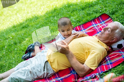 Image of grandfather and child in park using tablet