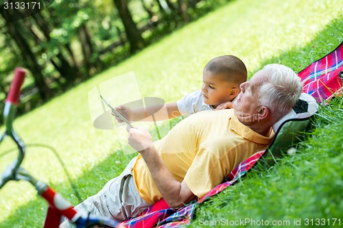 Image of grandfather and child in park using tablet