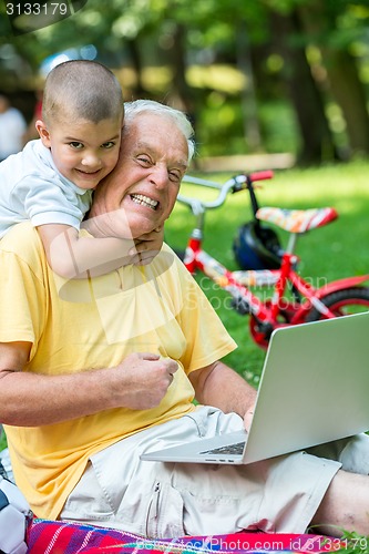 Image of grandfather and child using laptop