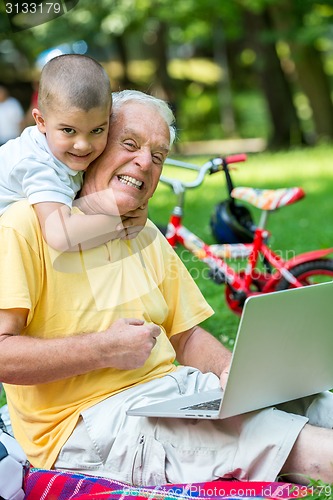 Image of grandfather and child using laptop