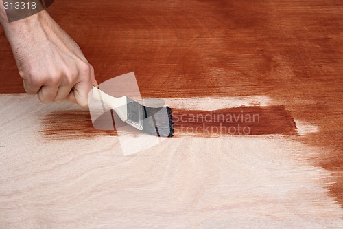 Image of Man's hand painting a wooden surface