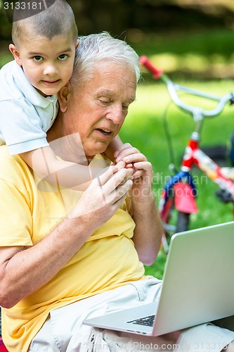 Image of grandfather and child using laptop