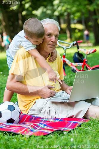 Image of grandfather and child using laptop