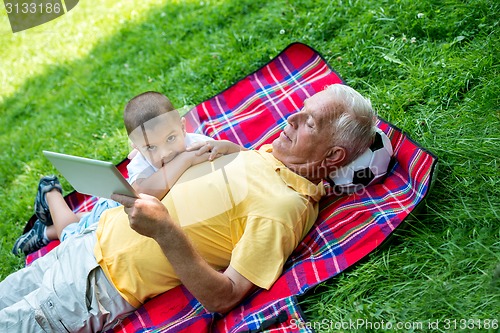 Image of grandfather and child in park using tablet