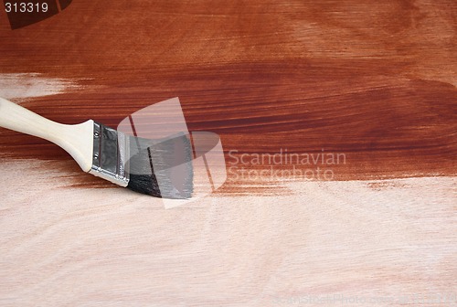 Image of Paint brush painting a wooden surface