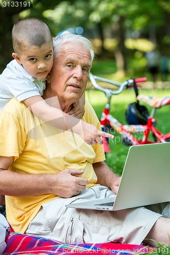 Image of grandfather and child using laptop