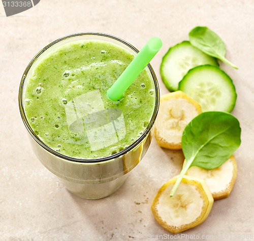 Image of glass of banana, spinach and cucumber smoothie with a straw